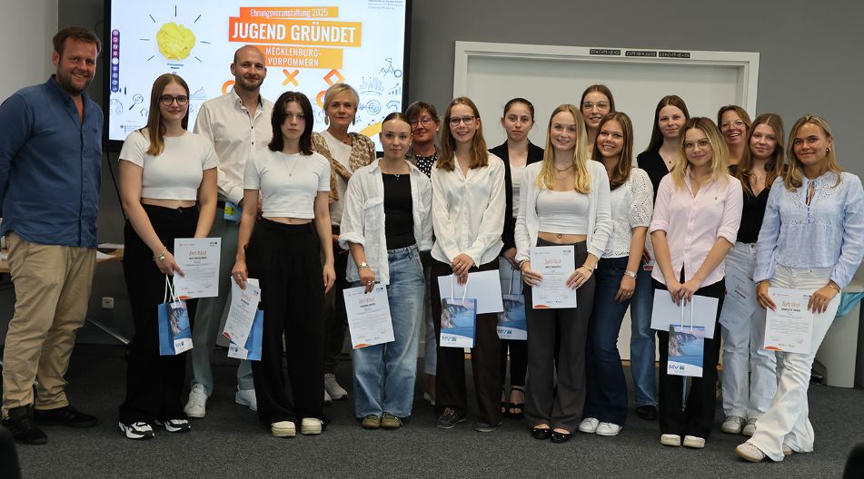 Gruppenfoto von Jugendlichen mit Zertifikaten und Erwachsenen vor einem Bildschirm mit der Aufschrift „Jugend gründet – Mecklenburg-Vorpommern – Ehrungsveranstaltung 2025“.