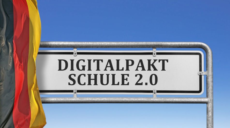 Ein Schild mit der Aufschrift "Digitalpakt Schule 2.0". Links vom Schild hängt eine Deutschlandfahne.