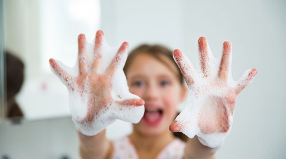 Ein Kind hält lachend seine mit Schaum bedeckten Hände in die Kamera, während es sich die Hände wäscht. Ein Kind hält lachend seine mit Schaum bedeckten Hände in die Kamera, während es sich die Hände wäscht.
