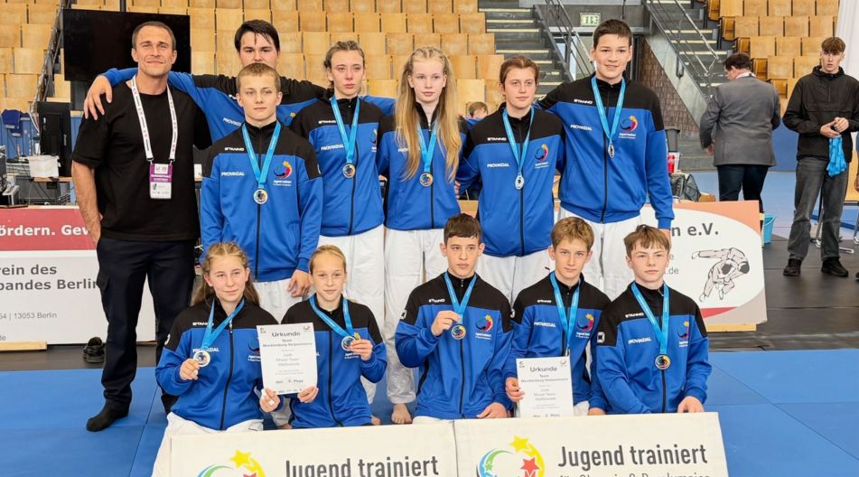 Eine Judo-Schulmannschaft mit Medaillen und Urkunden posiert bei „Jugend trainiert für Olympia & Paralympics“.