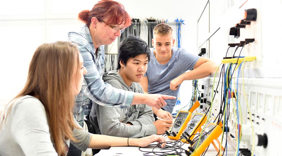 Eine Gruppe von jungen Menschen arbeitet gemeinsam an Elektronikprojekten in einem Ingenieurlabor. Eine Gruppe von jungen Menschen arbeitet gemeinsam an Elektronikprojekten in einem Ingenieurlabor.