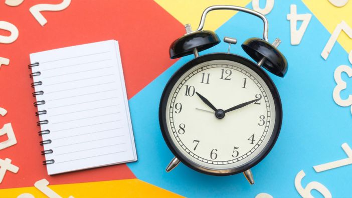 Uhr und Notizblock auf bunten Hintergrund Eine Uhr und ein Notizblock auf einem bunten Hintergrund mit Zahlen