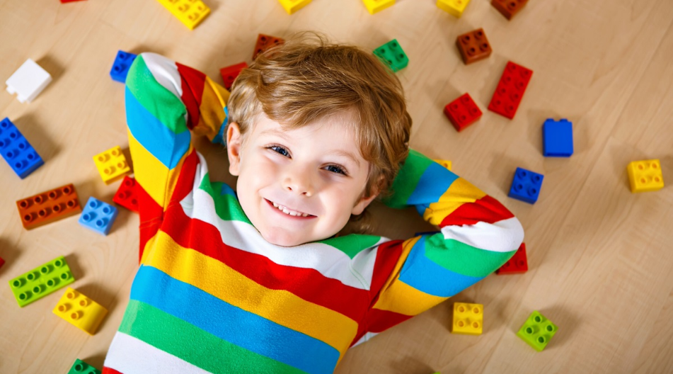 Ein Kind liegt auf dem Rücken, um ihn herum liegen Lego-Steine. Ein Kind liegt auf dem Rücken, um ihn herum liegen Lego-Steine.