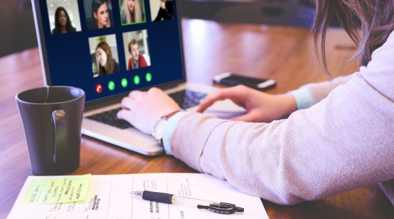 Eine Frau sitzt mit einem Laptop am Schreibtisch und hält eine Videokonferenz ab Eine Frau sitzt mit einem Laptop am Schreibtisch und hält eine Videokonferenz ab